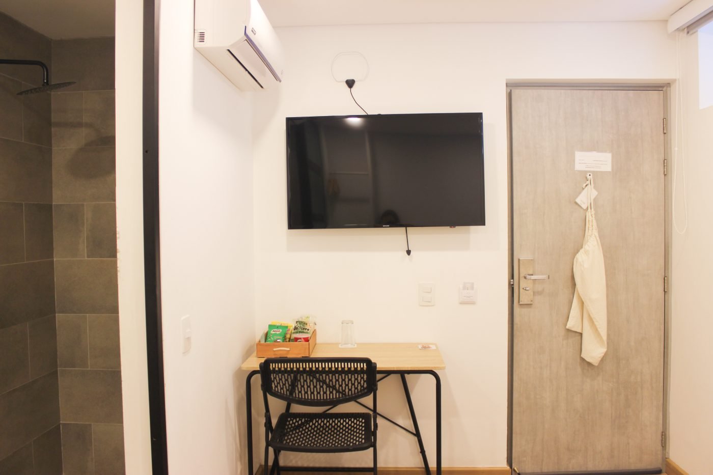 Habitación Sencilla con TV en pared, escritorio y ducha abierta