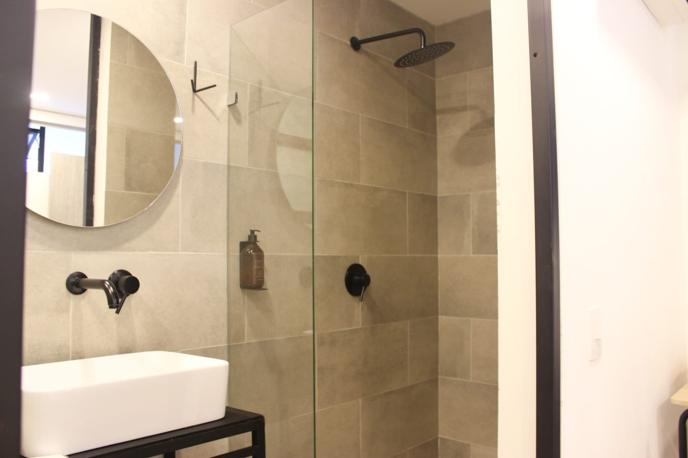 Baño de la Habitación Sencilla con lavamanos de sobreponer, espejo redondo y ducha de lluvia